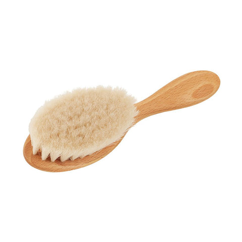 Eine Bürste für Babyhaar mit einem ovalen Kopf aus weichen Ziegenhaarborsten und einem kurzen Griff aus hellem Holz.